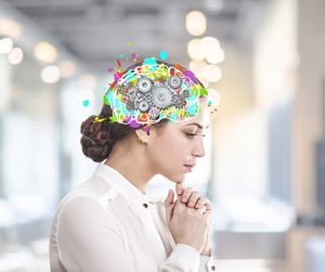 Žena u bijeloj košulji s ilustracijom mozga koji sadrži zupčanike i šarene elemente.