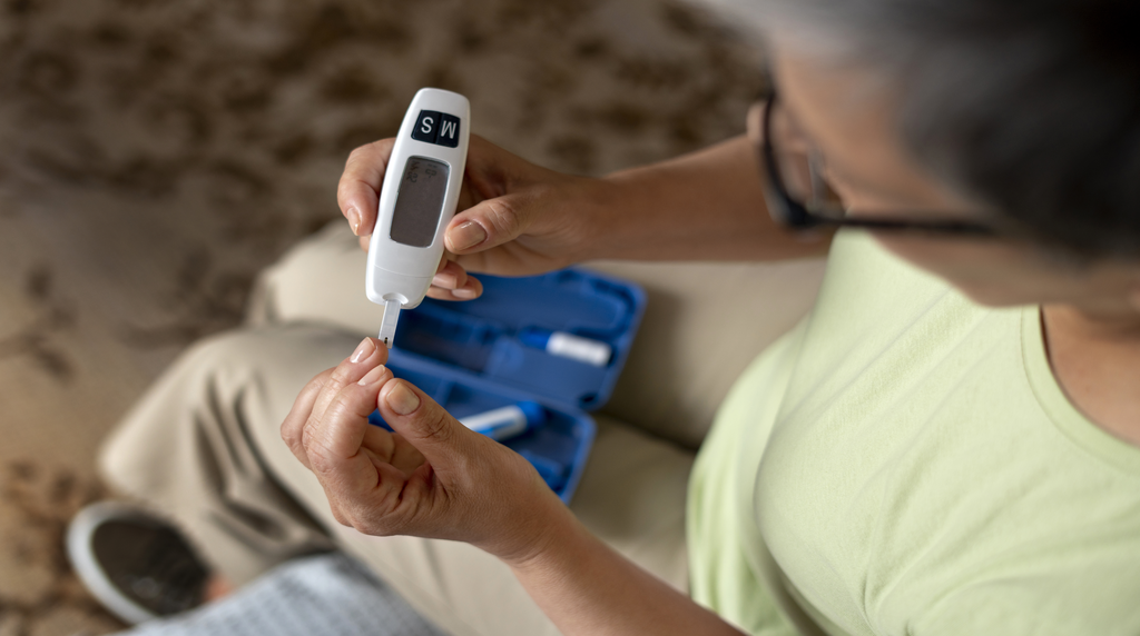 Žena s dijabetesom provjerava razinu glukoze u krvi pomoću glukometra kao dio svakodnevne kontrole šećera.